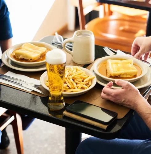 Table garnie de spécialités portugaises dont la Francesinha